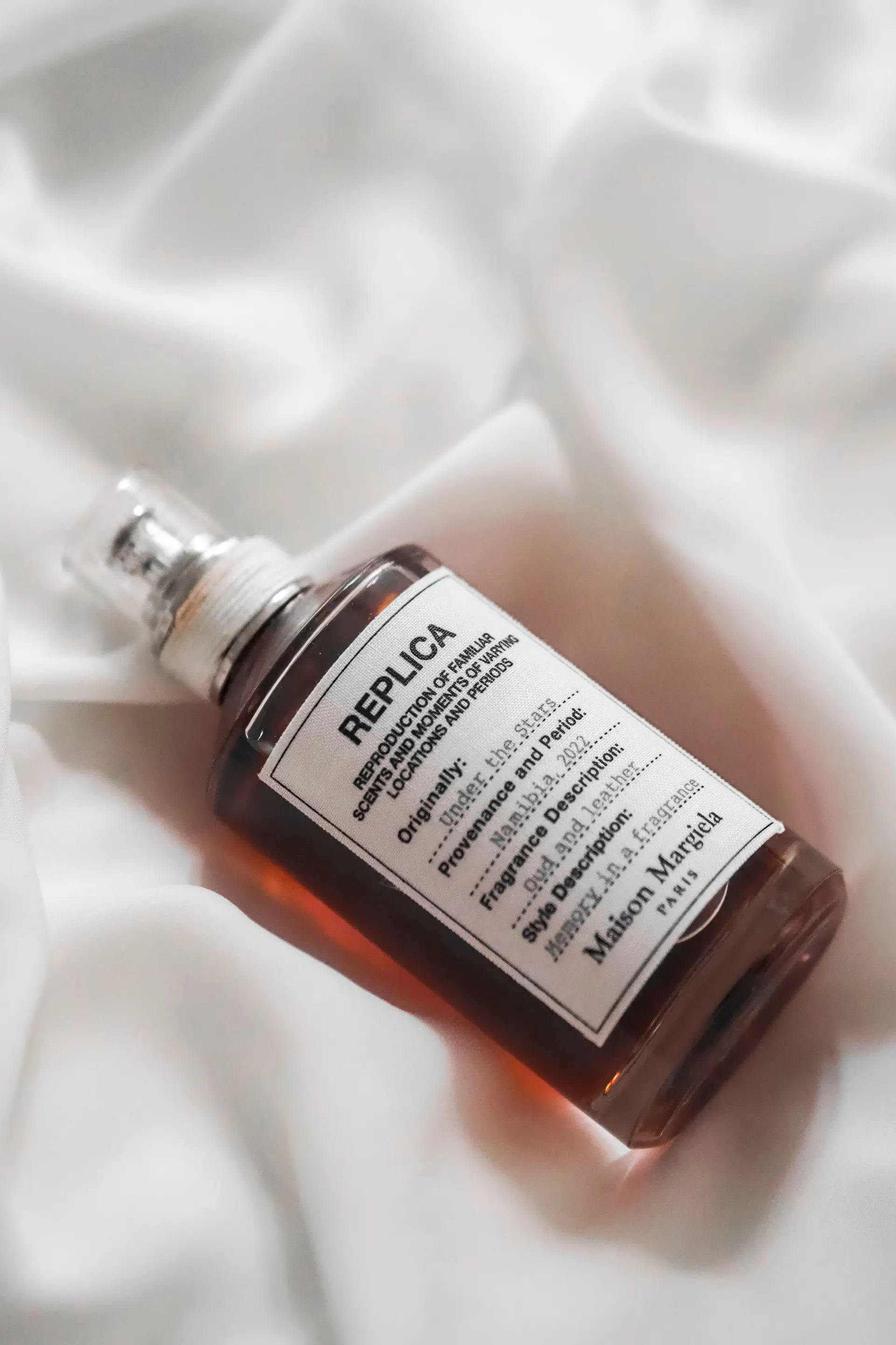 Fragrance bottle on soft white fabric suggesting clean woody notes